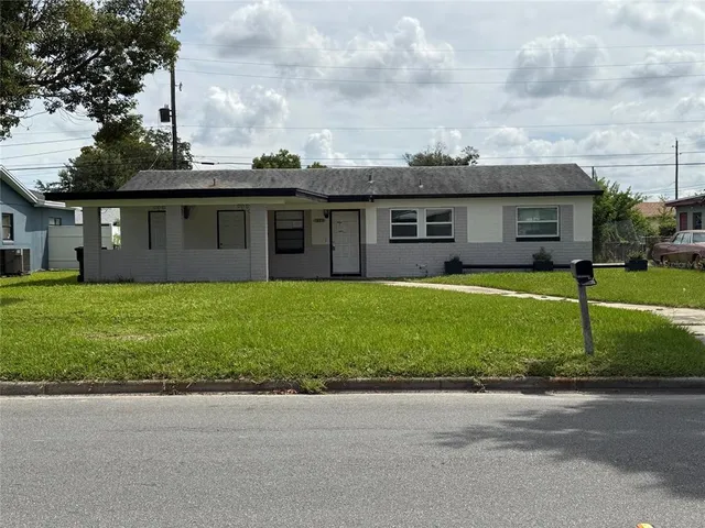 a view of a house with a yard and a large tree
