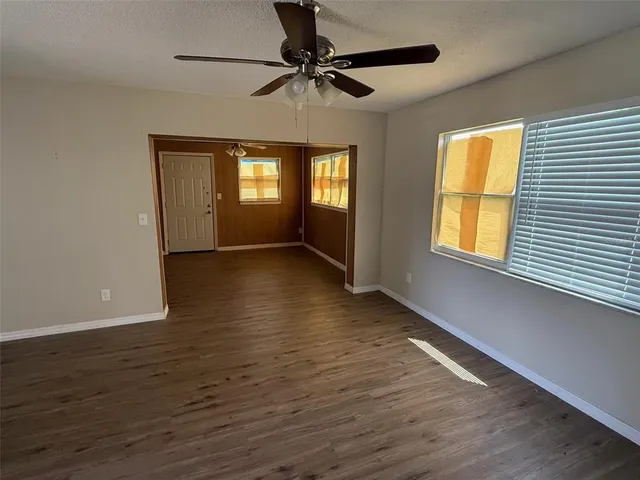 a view of an empty room with window and wooden floor