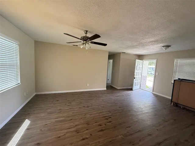 a view of an empty room with window and wooden floor