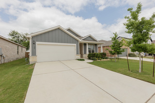 125 Janice Road Taylor, TX 76574 - Photo 24 of 26 Single-story residence featuring a two-car garage, board-and-batten siding with stone accents, a covered entry, a concrete driveway, and mature landscaping