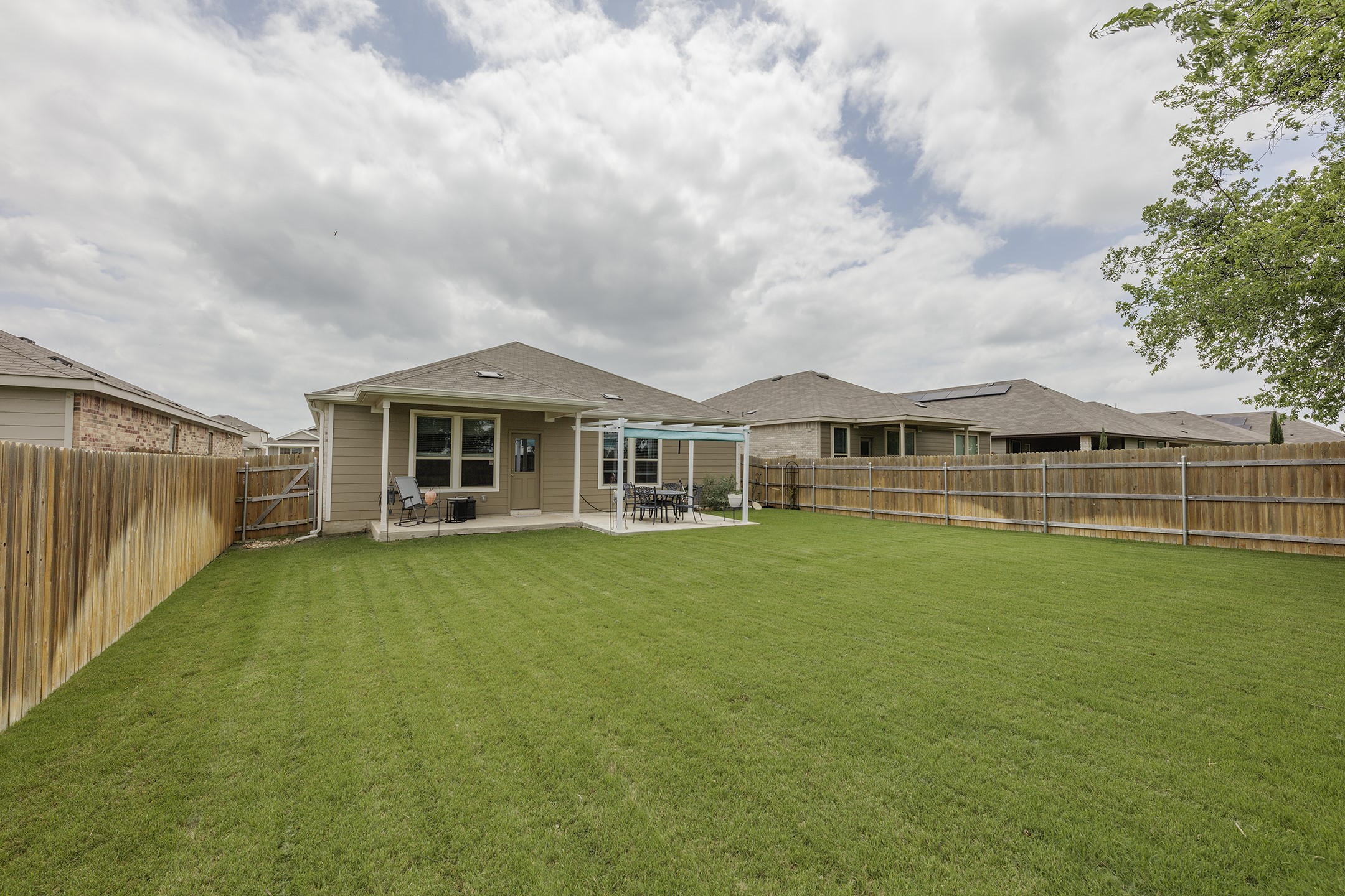 125 Janice Road Taylor, TX 76574 - Photo 25 of 26 Spacious backyard featuring a large green lawn, perimeter wood fencing, and a concrete patio