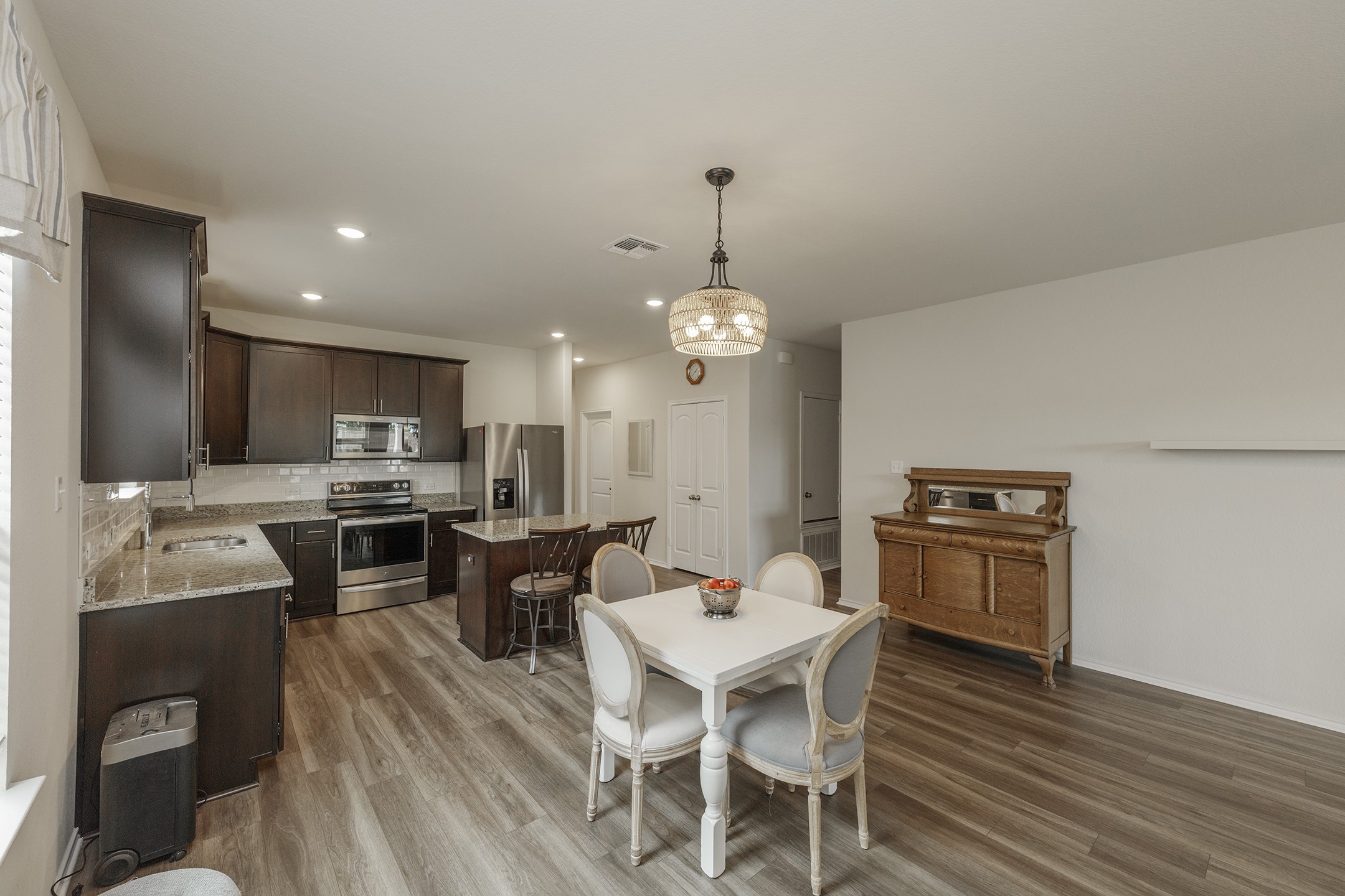 125 Janice Road Taylor, TX 76574 - Photo 3 of 26 Open-concept kitchen featuring dark wood cabinetry, stainless steel appliances, granite countertops, and a tile backsplash