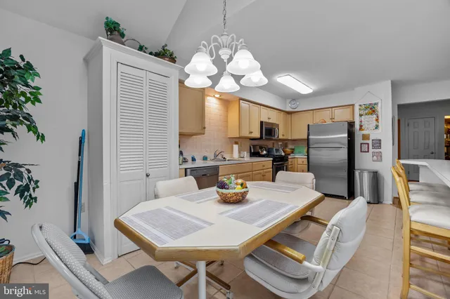 a kitchen with stainless steel appliances granite countertop a refrigerator a sink dishwasher a dining table and chairs with wooden floor