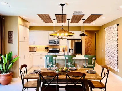 a dining room with stainless steel appliances a dining table chairs and couches