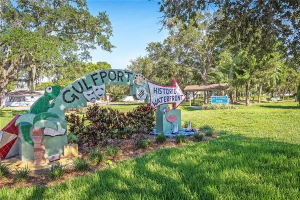 a view of a sign board with large trees