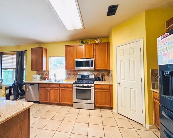 a kitchen with stainless steel appliances granite countertop a stove a sink and a refrigerator
