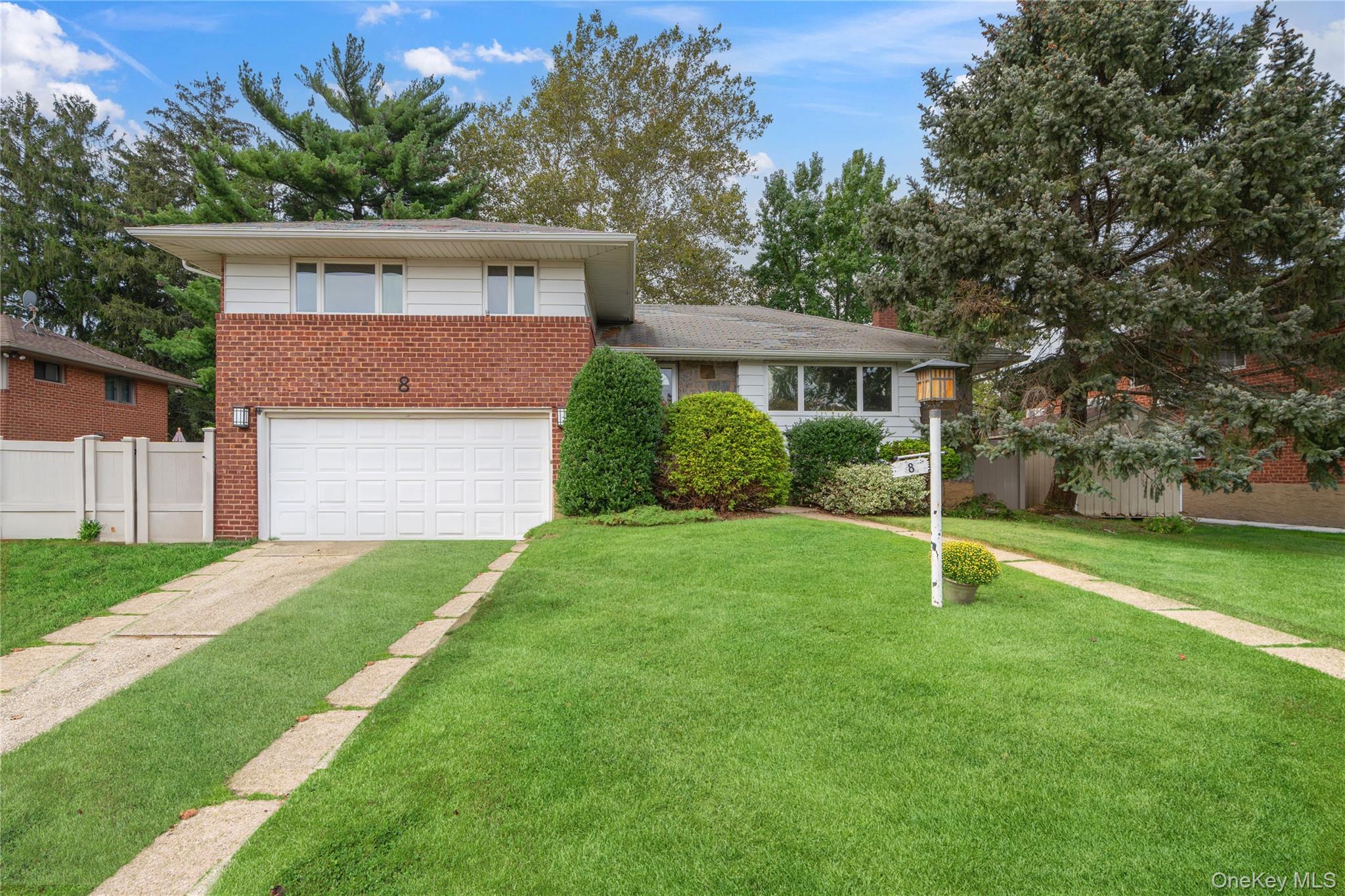 Tri-level home featuring brick siding, concrete driveway, and a garage