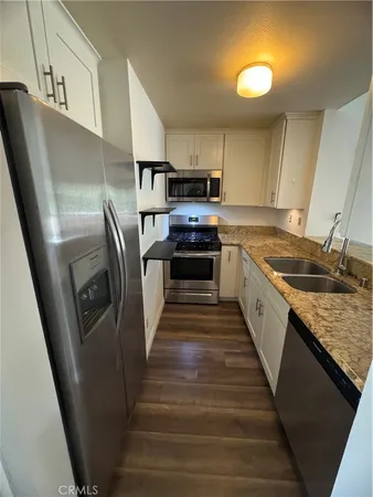 a kitchen with stainless steel appliances granite countertop a refrigerator a stove and a sink