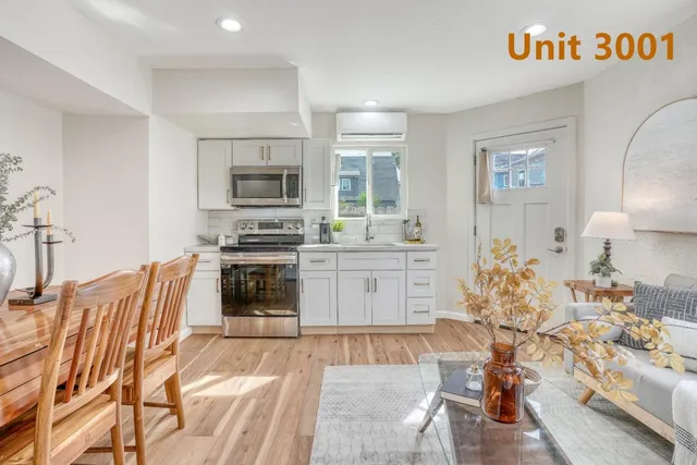 a kitchen with stainless steel appliances a stove a sink dishwasher a oven with white cabinets and wooden floor