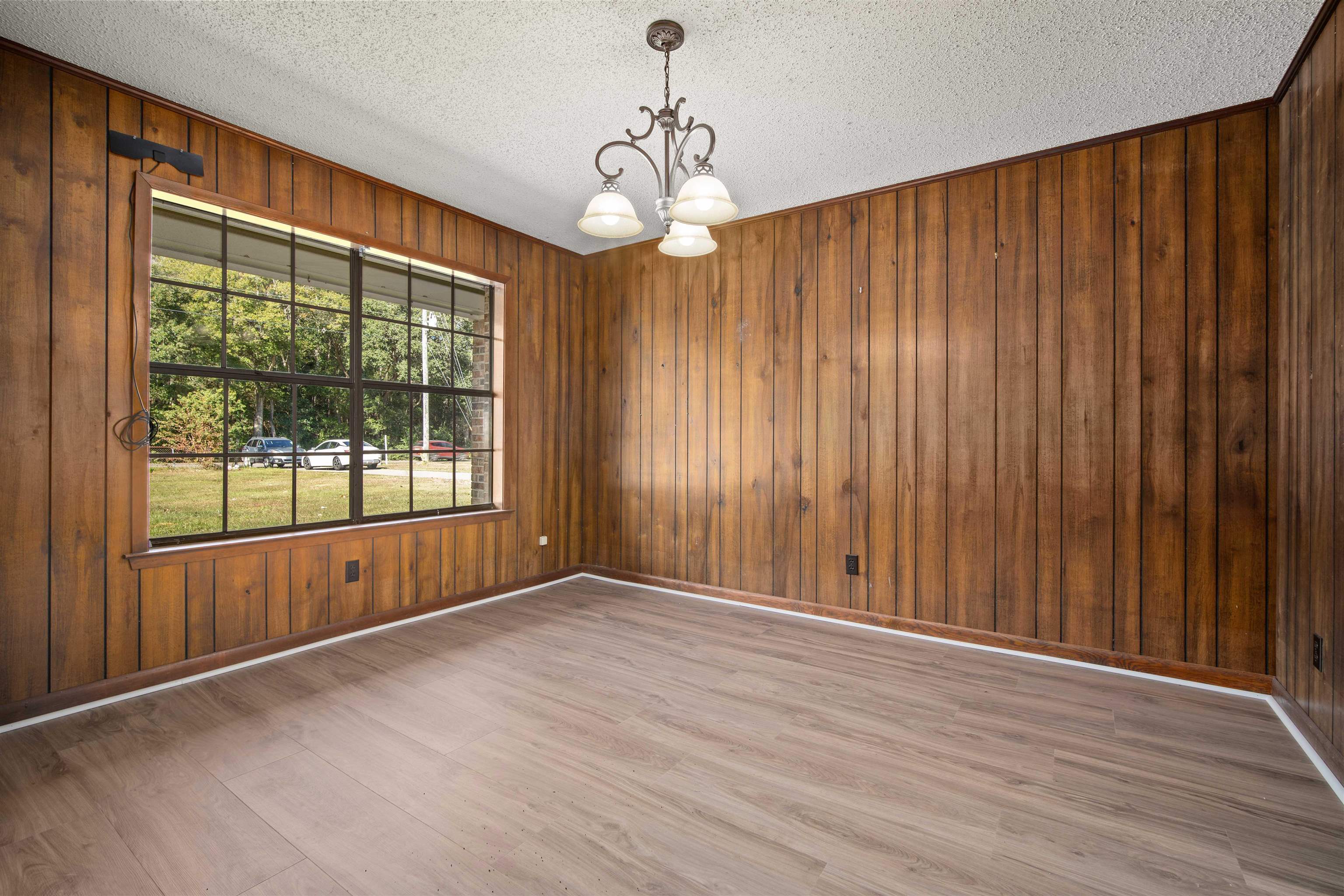 10285 Argyle Road Irvington, AL 36544 - Photo 14 of 28 Spare room featuring a chandelier, light wood-style floors, a textured ceiling, and wooden walls