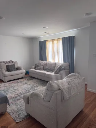 a living room with couches and dresser with wooden floor