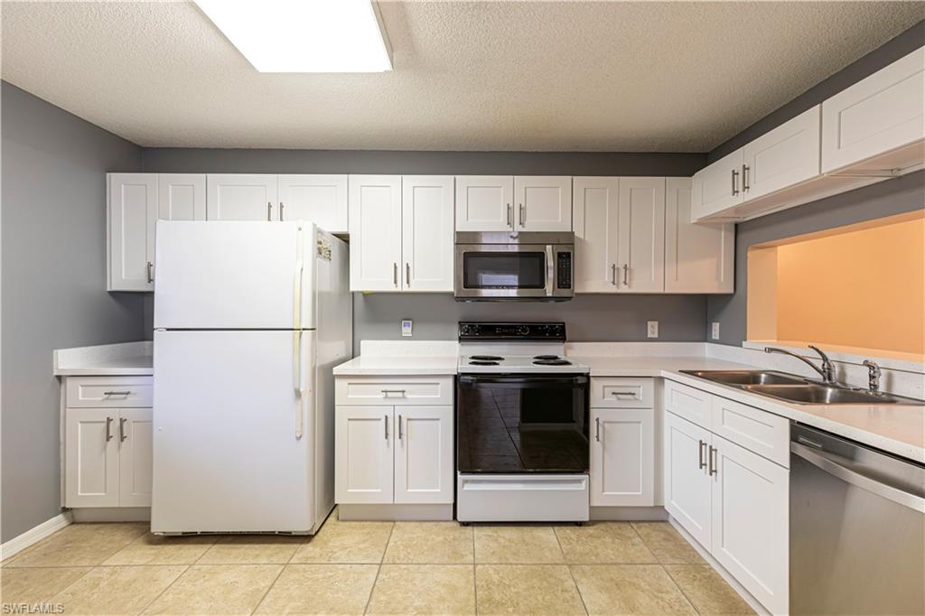 7761 Jewel Lane, Unit 202 Naples, FL 34109 - Photo 13 of 27 Kitchen with sink, white cabinets, a textured ceiling, and appliances with stainless steel finishes