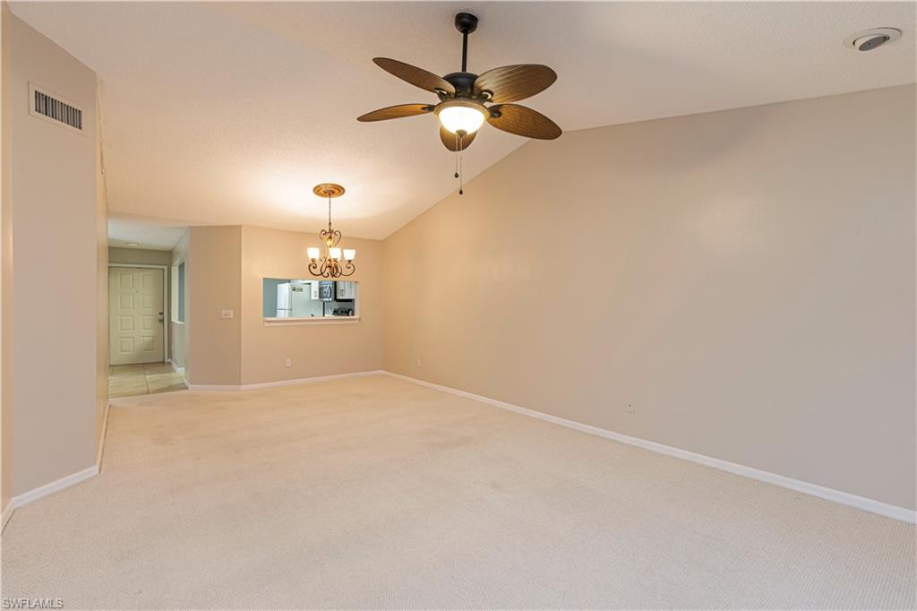 7761 Jewel Lane, Unit 202 Naples, FL 34109 - Photo 5 of 27 Spare room with light carpet, ceiling fan with notable chandelier, and lofted ceiling