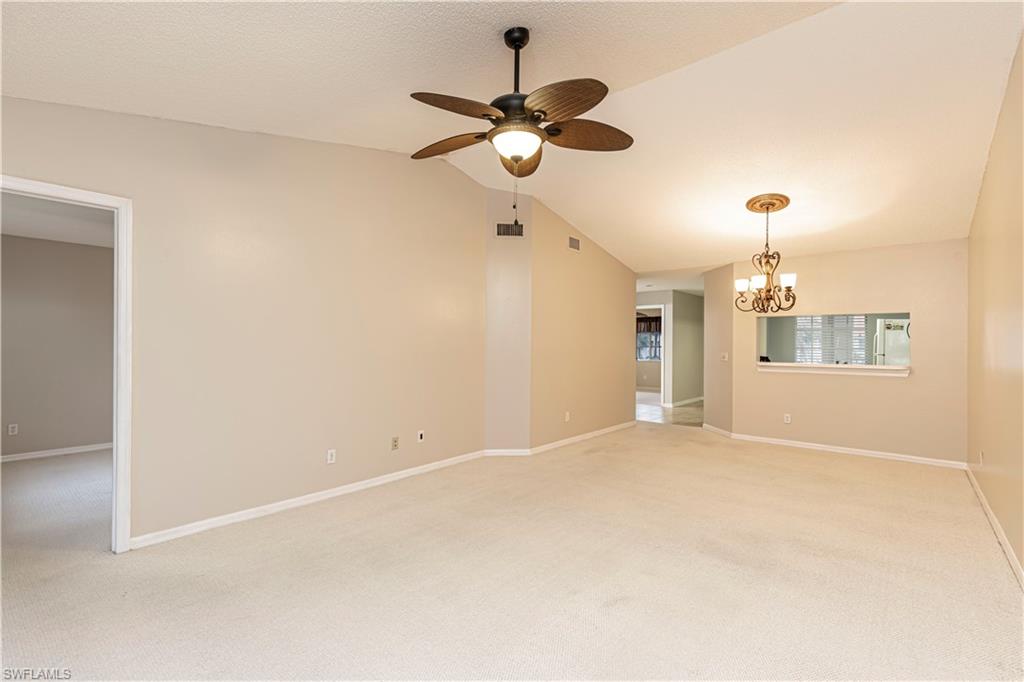 7761 Jewel Lane, Unit 202 Naples, FL 34109 - Photo 6 of 27 Carpeted spare room featuring ceiling fan with notable chandelier and lofted ceiling