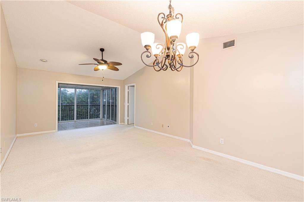 7761 Jewel Lane, Unit 202 Naples, FL 34109 - Photo 7 of 27 Spare room featuring ceiling fan with notable chandelier, carpet floors, and vaulted ceiling