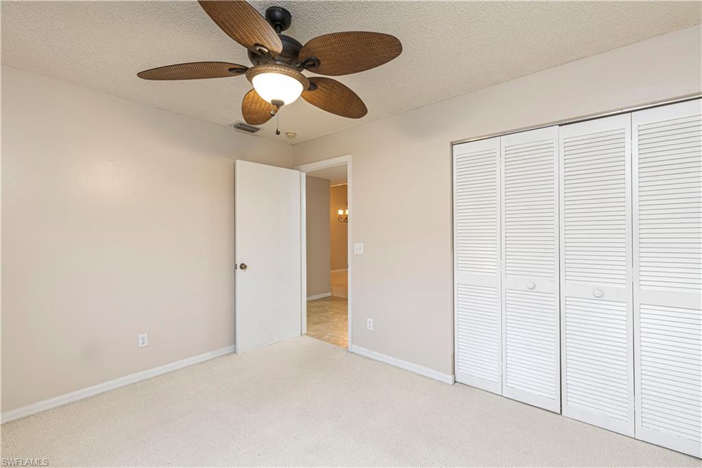 7761 Jewel Lane, Unit 202 Naples, FL 34109 - Photo 9 of 27 Unfurnished bedroom featuring ceiling fan, light colored carpet, a textured ceiling, and a closet