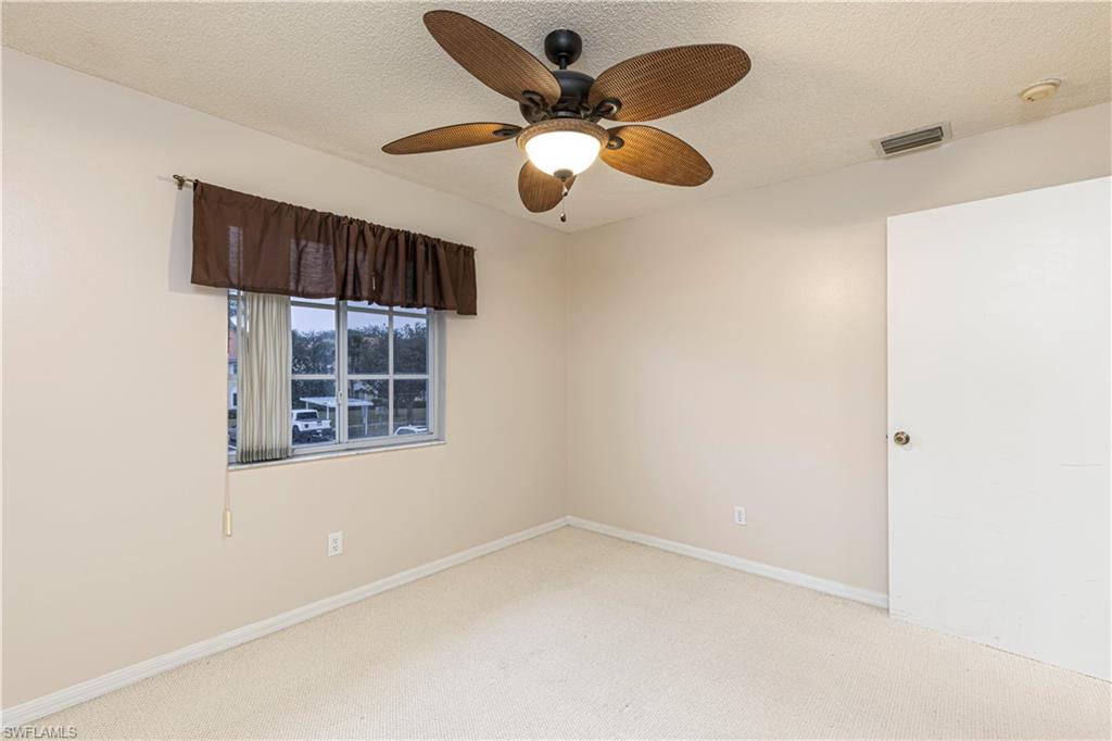 7761 Jewel Lane, Unit 202 Naples, FL 34109 - Photo 10 of 27 Unfurnished room with a textured ceiling, light colored carpet, and ceiling fan