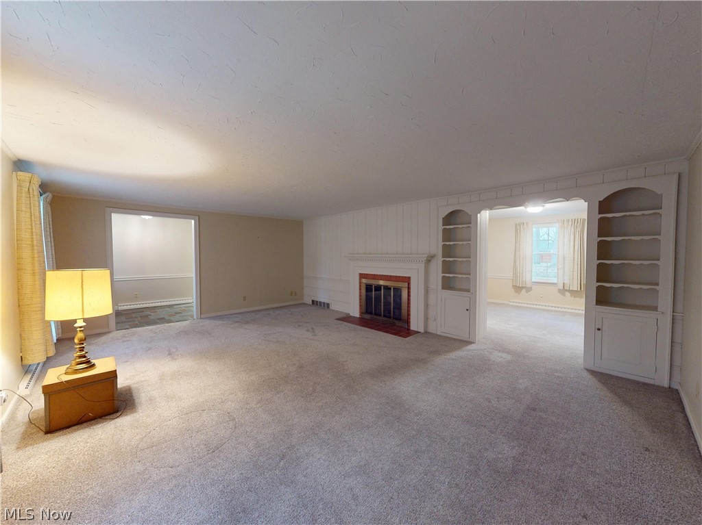 145 Overlook Road Painesville, OH 44077 - Photo 31 of 36 Unfurnished living room featuring built in features, carpet flooring, a fireplace with flush hearth, and a baseboard radiator
