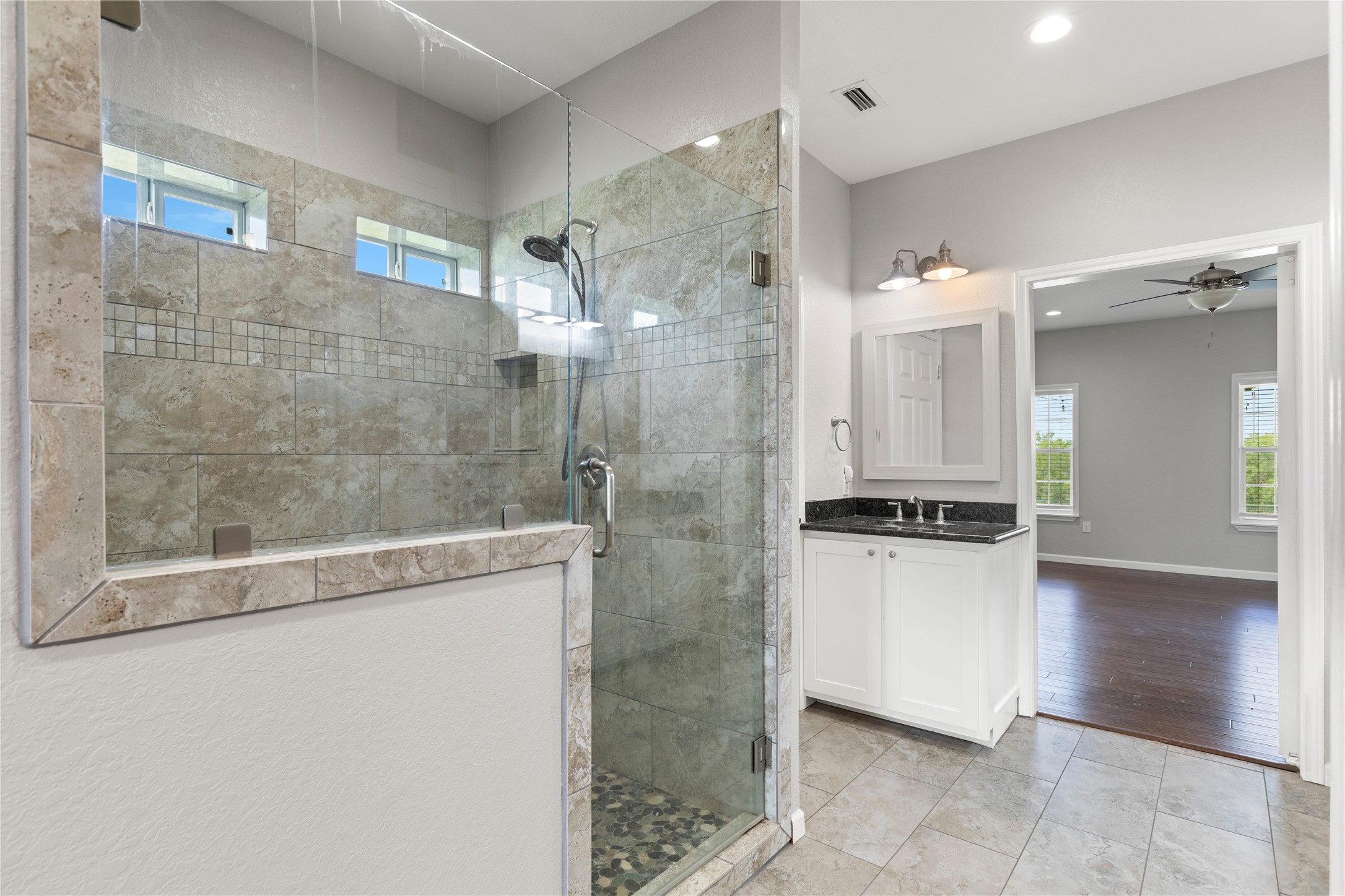 1293 Pioneer Road Seguin, TX 78155 - Photo 18 of 40 A generous walk-in shower with natural stone tile and glass enclosure complements the bathroom's modern vanity.