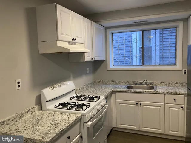 a kitchen with granite countertop a sink stove and cabinets