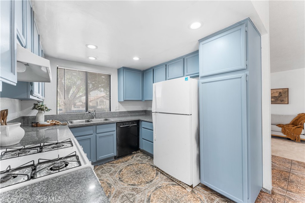 3542 East Ave R 10 Palmdale, CA 93550 - Photo 16 of 35 a kitchen with refrigerator a stove a sink dishwasher and a refrigerator with wooden floor