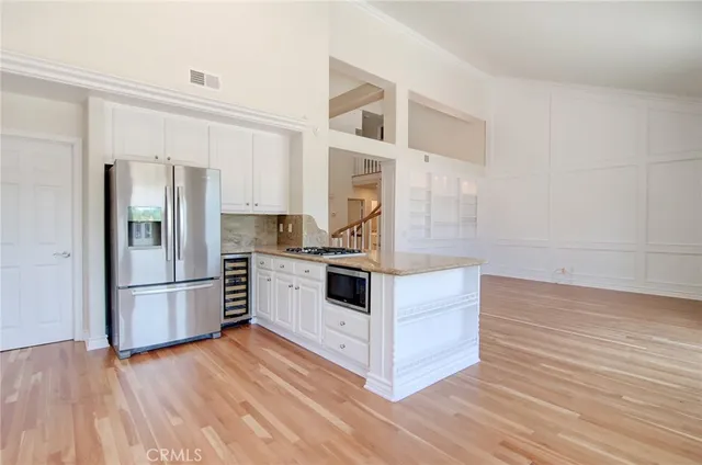a kitchen with stainless steel appliances a stove a white cabinets and a wooden floor