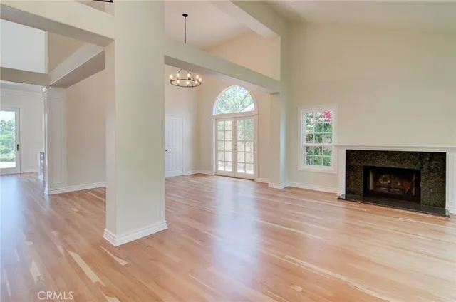 a view of an empty room with wooden floor fireplace and a window