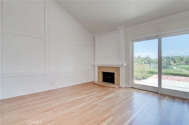 a view of empty room with wooden floor and fireplace