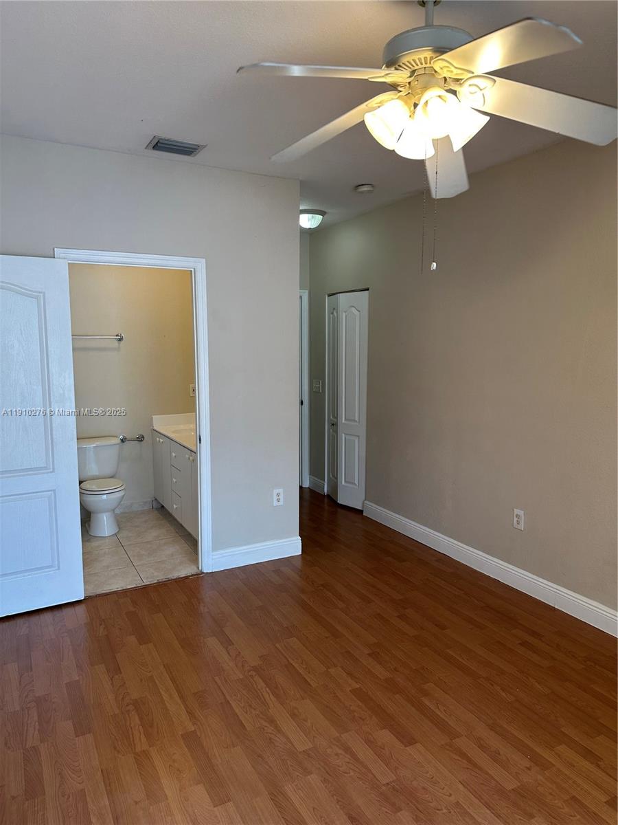 7549 Northwest 175th Street, Unit 7549 Hialeah, FL 33015 - Photo 21 of 34 a view of a room with wooden floor and a ceiling fan