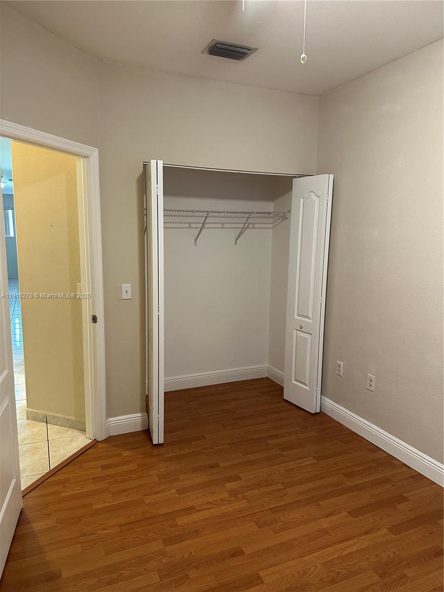 7549 Northwest 175th Street, Unit 7549 Hialeah, FL 33015 - Photo 29 of 34 an empty room with wooden floor and closet