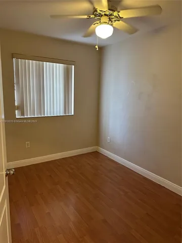 an empty room with wooden floor and mirror