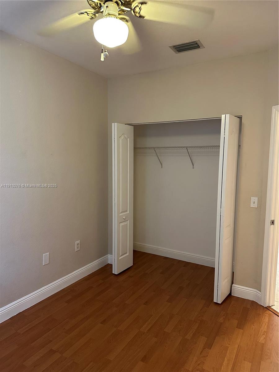 7549 Northwest 175th Street, Unit 7549 Hialeah, FL 33015 - Photo 31 of 34 an empty room with wooden floor and mirror