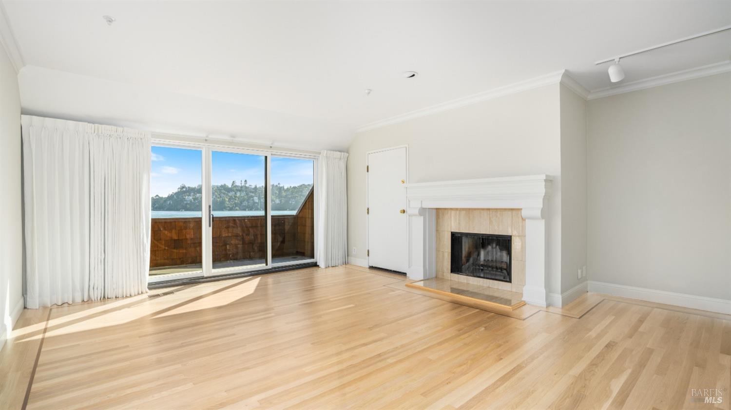206 Paradise Drive Tiburon, CA 94920 - Photo 23 of 45 a view of an empty room with wooden floor fireplace and a window