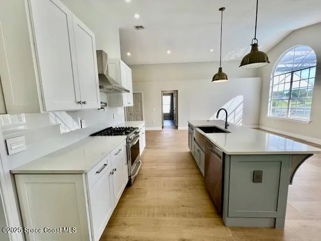 a kitchen with stainless steel appliances granite countertop a sink a stove and a wooden floors