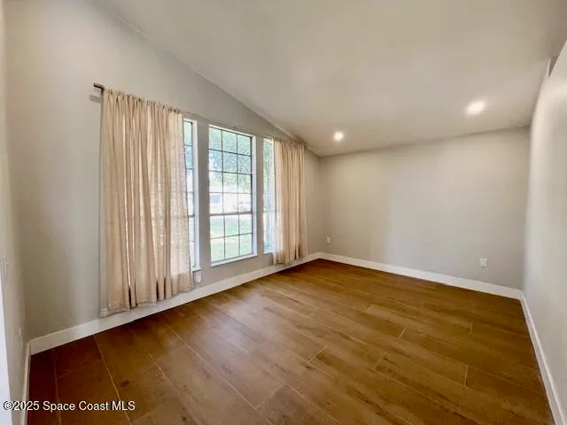 a view of an empty room with wooden floor and a window