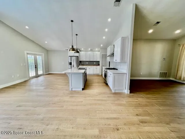 a view of a kitchen with kitchen island a counter top space a sink stainless steel appliances and cabinets