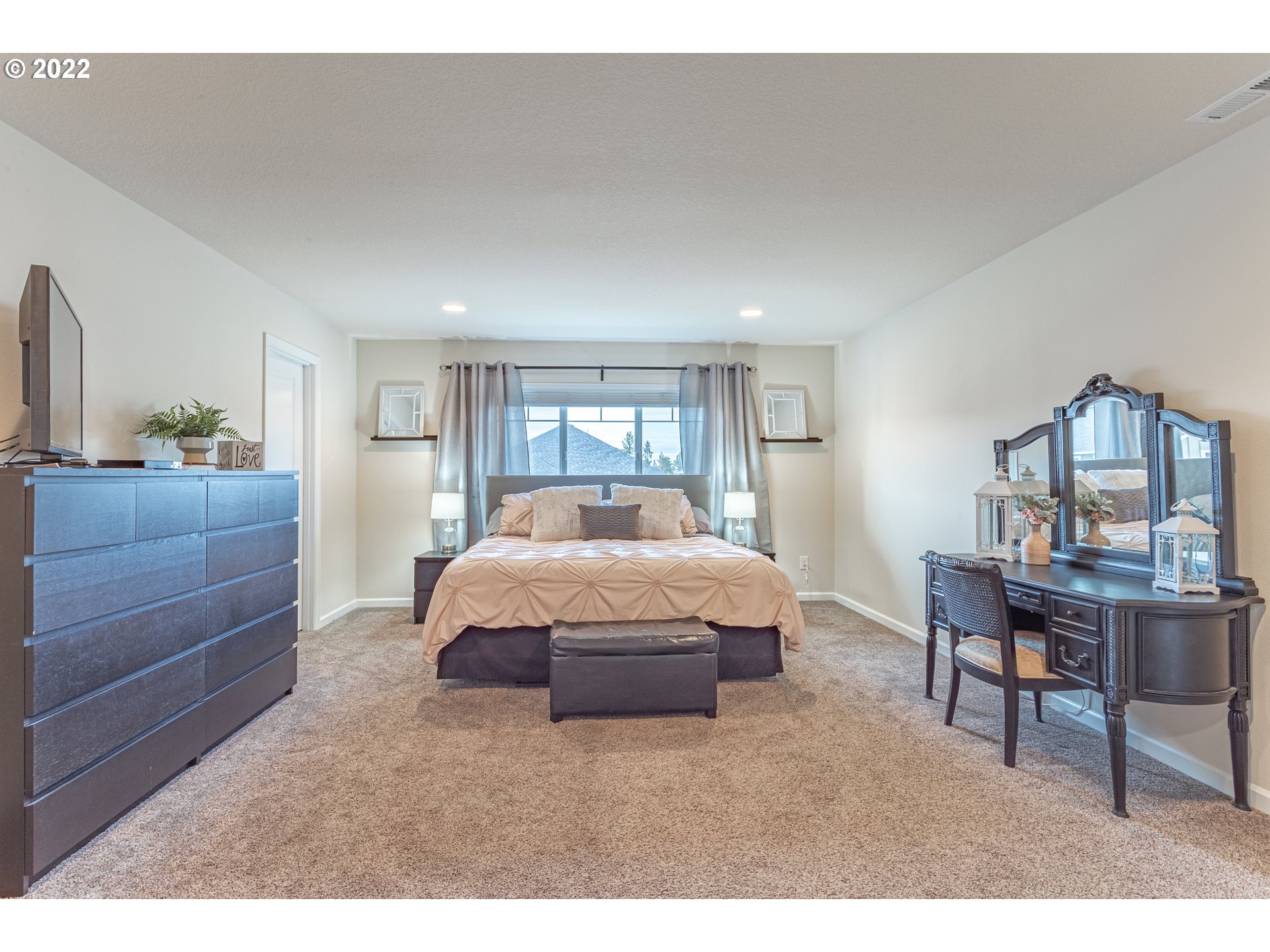 17656 Southeast Pinnacles Street Damascus, OR 97089 - Photo 4 of 31 a spacious bedroom with a bed table chair and a window
