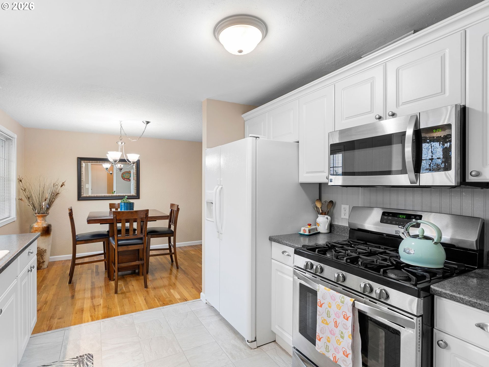 2036 Sallal Road Woodburn, OR 97071 - Photo 3 of 25 a kitchen with stainless steel appliances granite countertop a stove top oven a sink a dining table and chairs with wooden floor