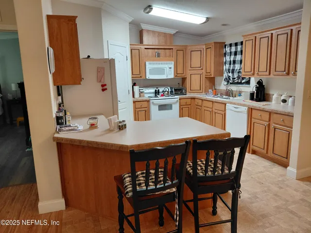 a kitchen with stainless steel appliances a dining table chairs refrigerator and sink