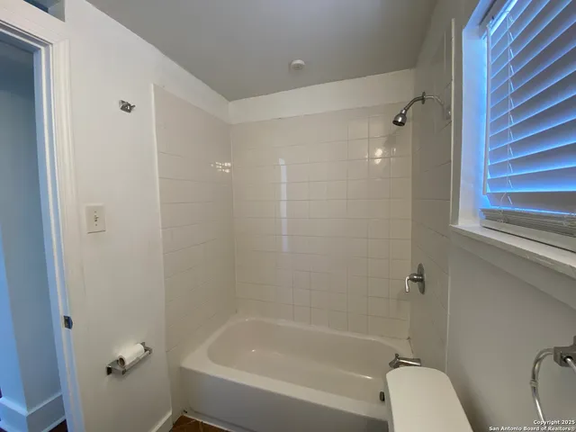 a bathroom with a granite countertop bathtub shower and toilet
