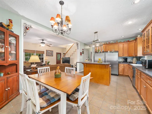 a view of a dining room and livingroom with furniture wooden floor a rug a flat screen tv a rug and a chandelier