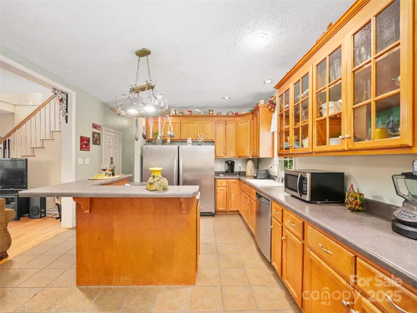 a large kitchen with kitchen island a large counter space a sink stainless steel appliances and cabinets
