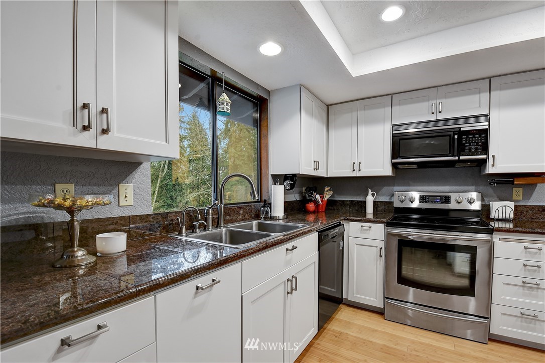 22217 61st Avenue Southeast Bothell, WA 98021 - Photo 11 of 37 a kitchen with stainless steel appliances granite countertop a sink a stove and a microwave