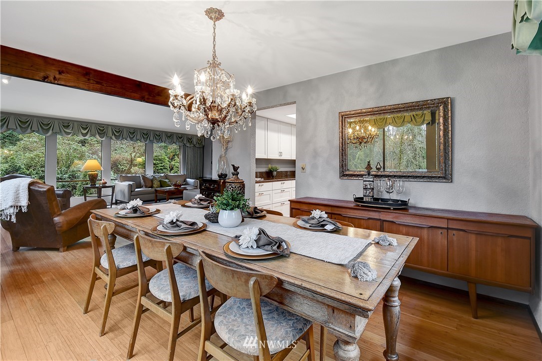 22217 61st Avenue Southeast Bothell, WA 98021 - Photo 8 of 37 a dining room with wooden floor a chandelier a glass table and chairs