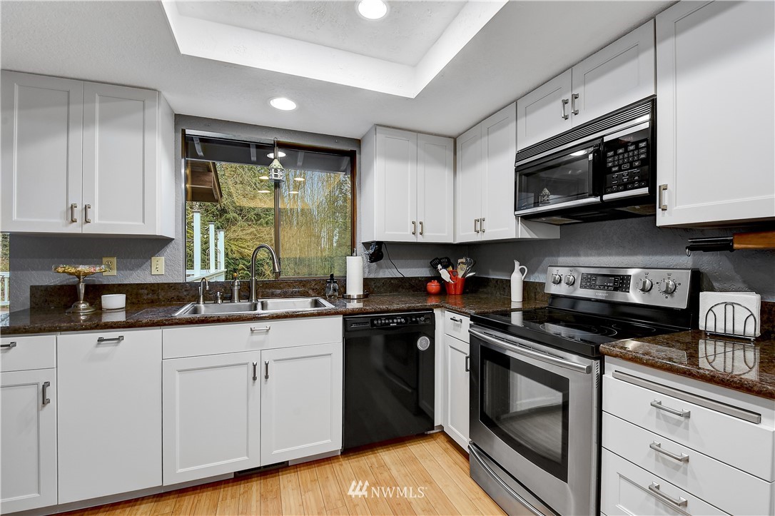 22217 61st Avenue Southeast Bothell, WA 98021 - Photo 10 of 37 a kitchen with stainless steel appliances granite countertop a sink a stove a microwave and cabinets