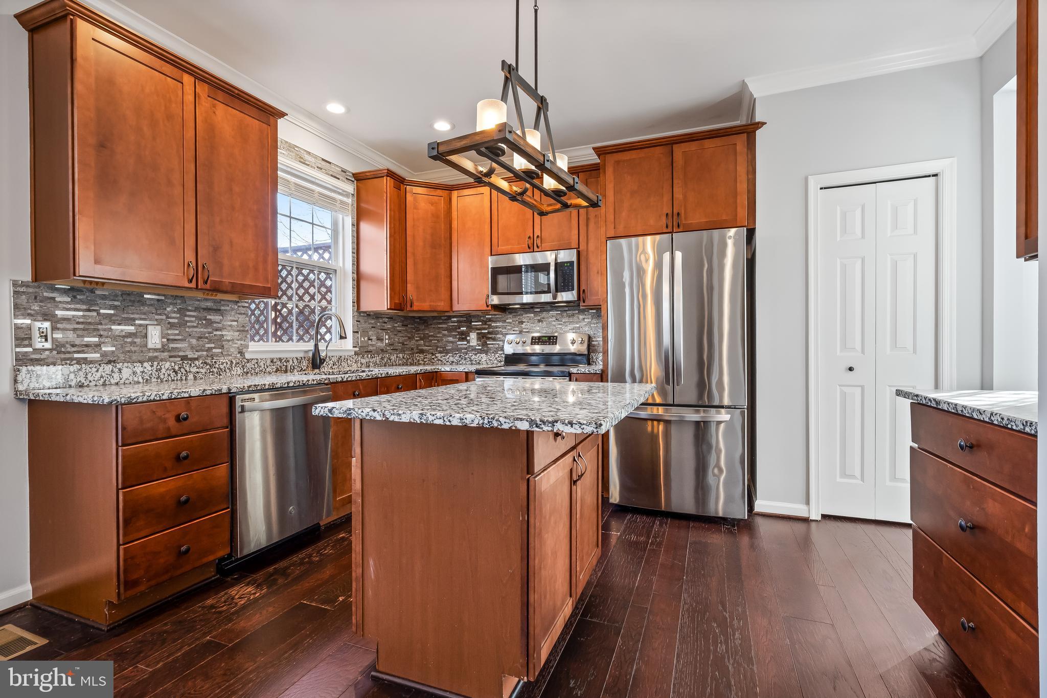 43112 Demerrit Street Chantilly, VA 20152 - Photo 8 of 42 a kitchen with stainless steel appliances granite countertop a refrigerator a sink dishwasher a stove and white countertops with wooden floor