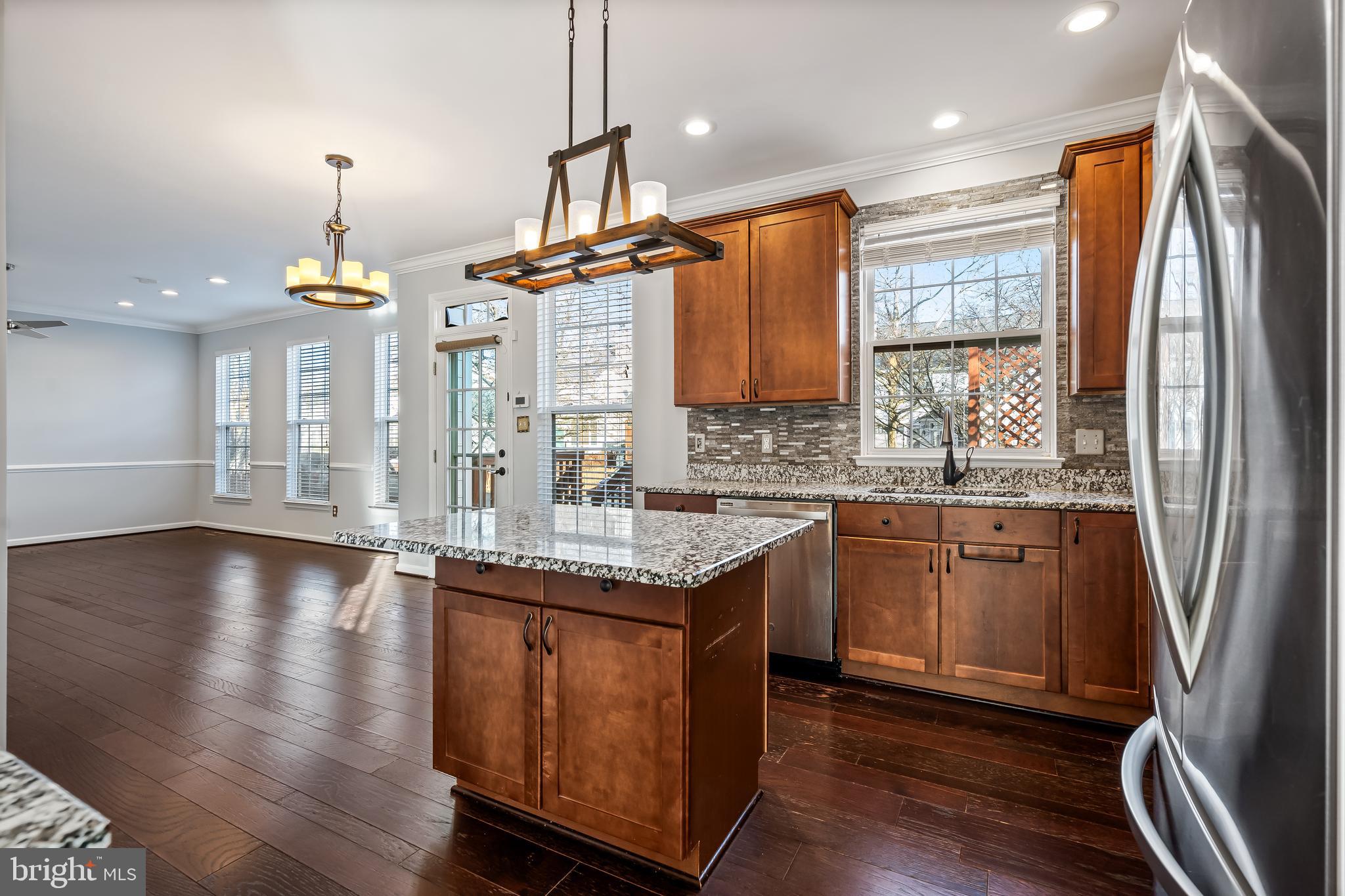 43112 Demerrit Street Chantilly, VA 20152 - Photo 10 of 42 a kitchen with stainless steel appliances granite countertop a refrigerator a sink dishwasher a stove and a dining table with wooden floor