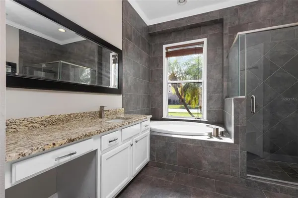 a bathroom with a granite countertop sink a mirror and a bathtub