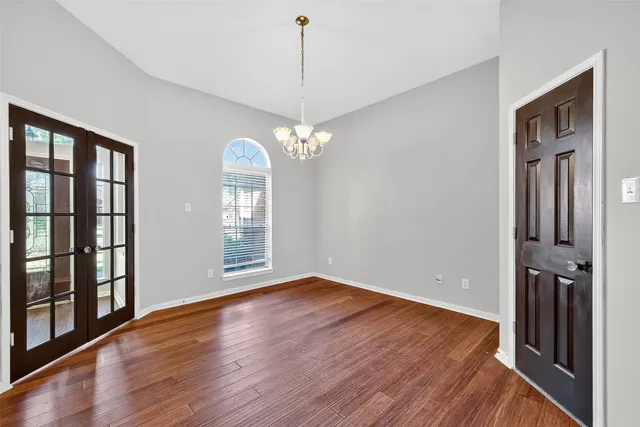 a view of a room with wooden floor chandeliers and kitchen view