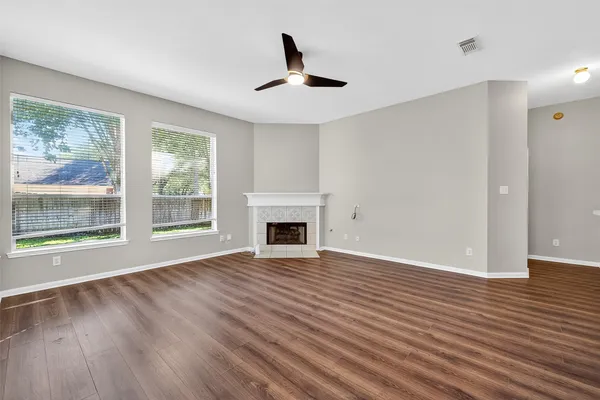 a view of an empty room with wooden floor and a window